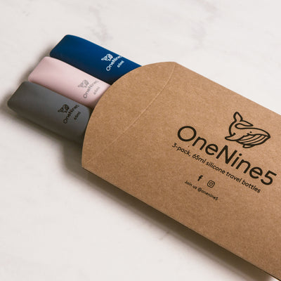 3 pack of mixed colour silicone travel bottles are packed inside brown, recyclable kraft paper. The packaging is branded with a black OneNine5 logo