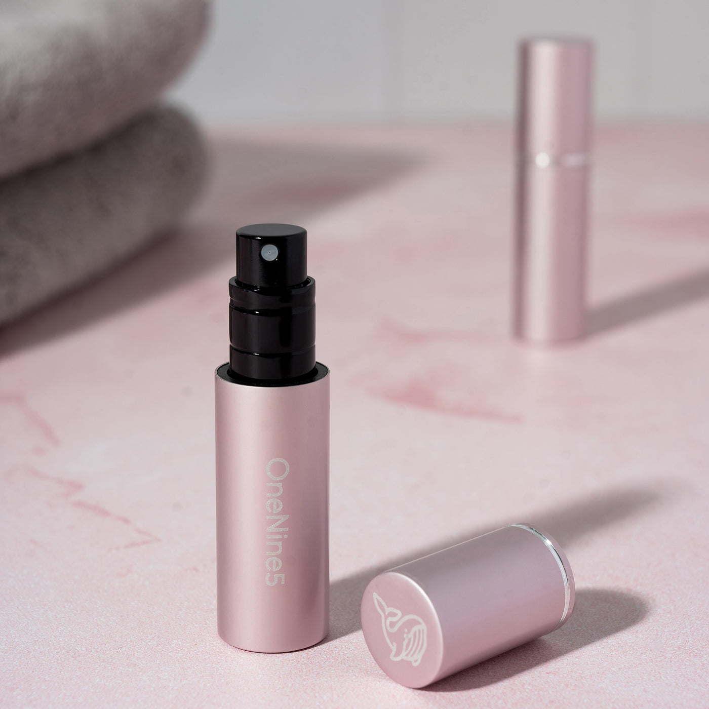 OneNine5 pink travel friendly fragrance bottle, with the magnetic lid removed and the pump visible