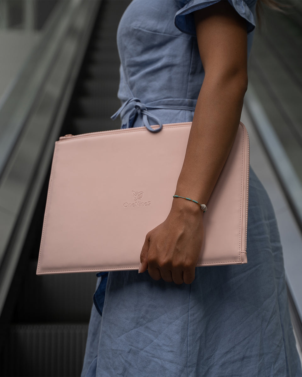 Female in a blue dress carrying the OneNine5 Komodo Pink, Eco-Conscious laptop sleeve up an escalator