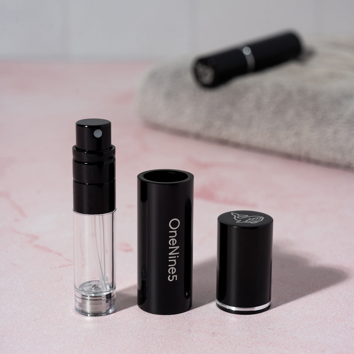The 3 components of the black OneNine5 refillable fragrance bottle - the images shows the pump, case and magentic lid in line