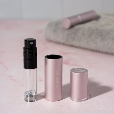 The 3 components of the pink OneNine5 refillable fragrance bottle - the images shows the pump, case and magnetic lid in line.