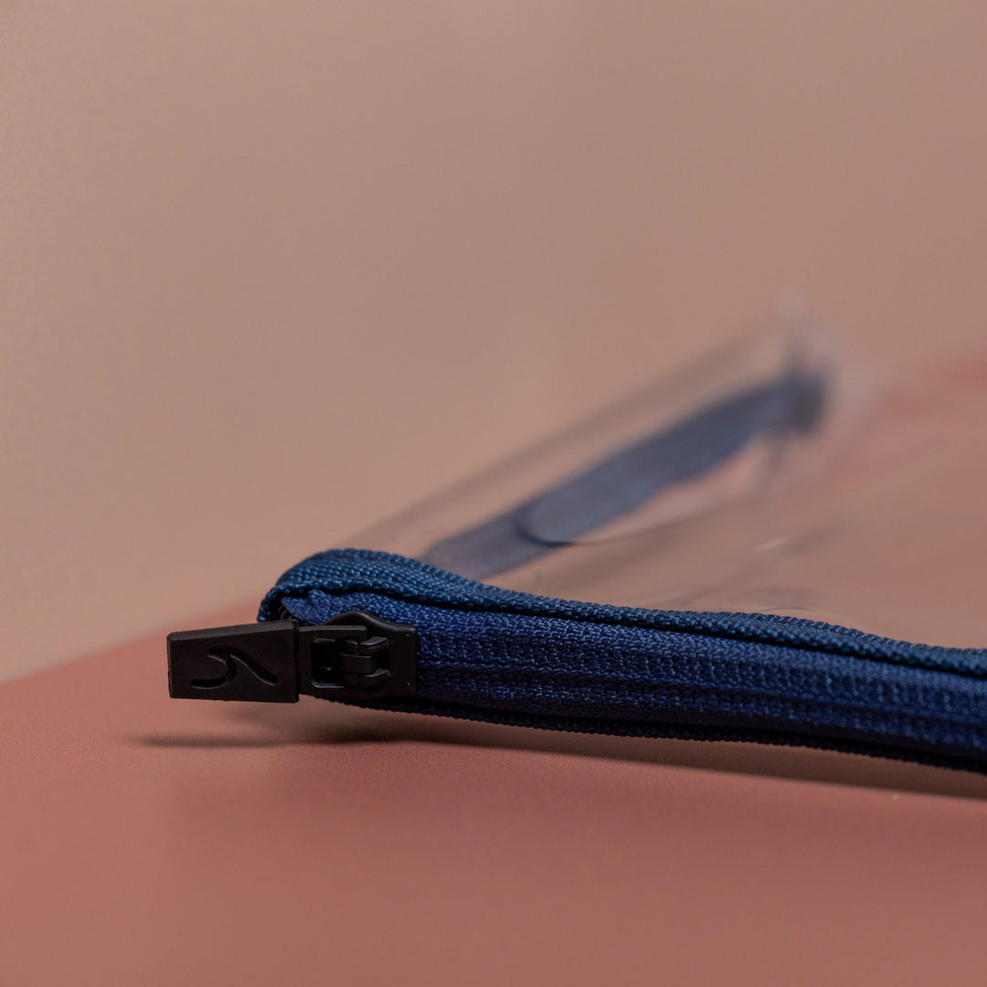 Close-up of blue clear liquid pouch zip with black debossed wave pull detail and durable fabric trim