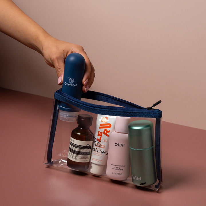 Hand placing travel toiletries into blue clear liquid pouch designed for airport security liquids and carry-on packing