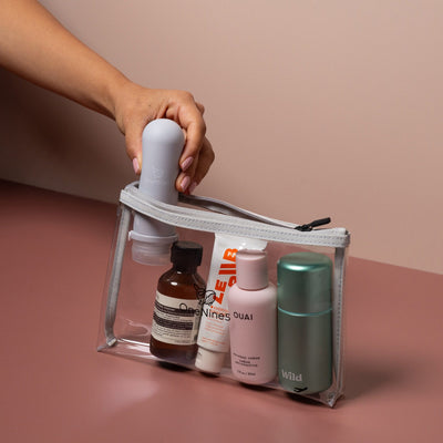 Hand packing toiletries into grey clear liquid pouch designed for airport liquids and carry-on travel