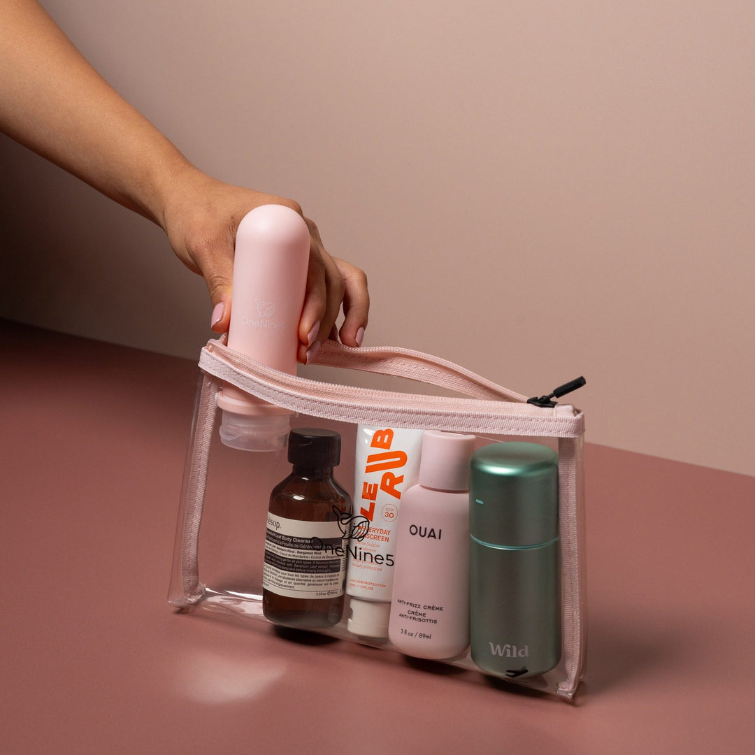 Hand placing toiletries into pink clear liquid pouch designed for airport security liquids and organised travel