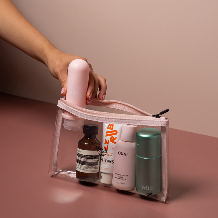 Hand placing toiletries into pink clear liquid pouch designed for airport security liquids and organised travel