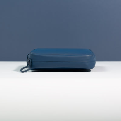 Side profile of the Havelock Blue Eco Essentials Pouch on a white surface with a blue background. Image shows detail of outer blue waterproof zipper tape and metal O-ring zip puller.