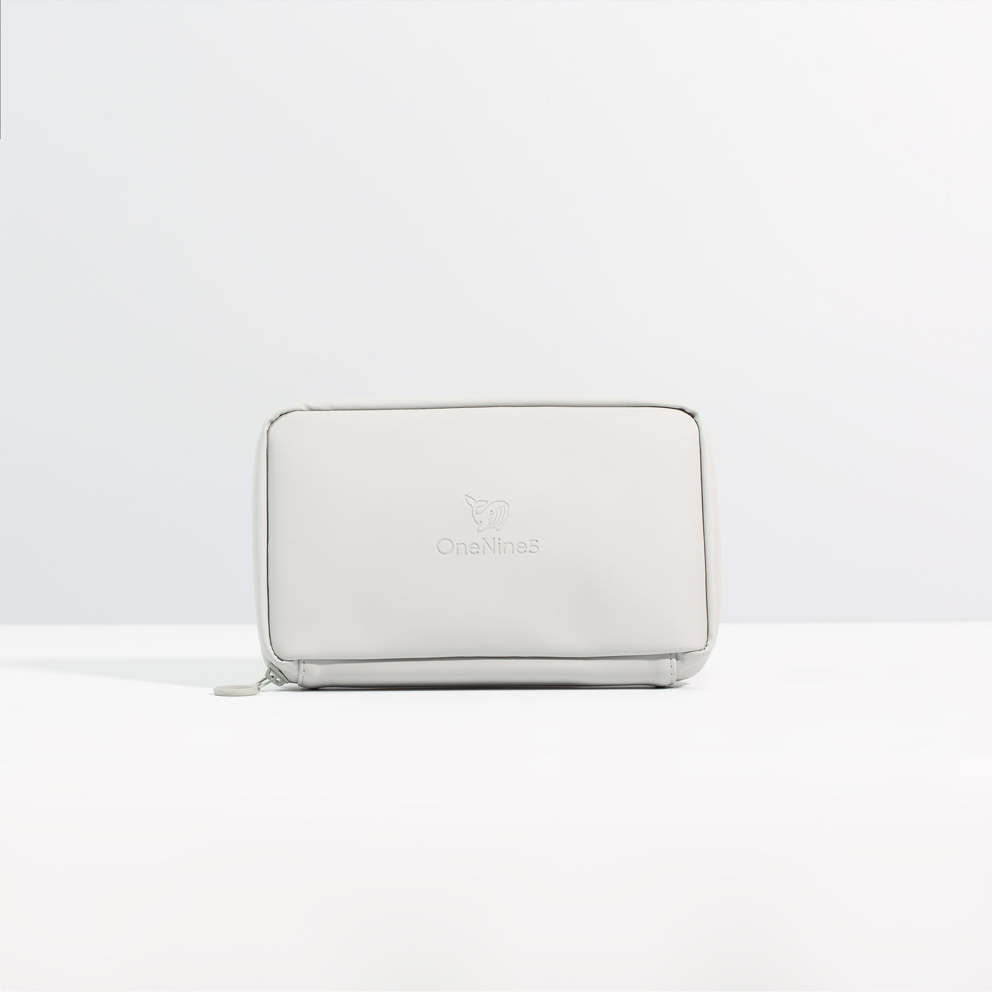 A front on view of the Moeraki Grey Eco Essentials Pouch. Placed on a white surface with a grey background. The debossed OneNine5 logo is visible centrally on the front of the pouch.