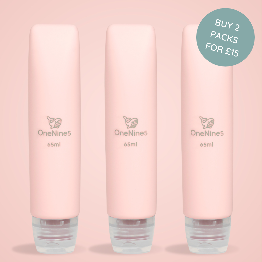 Three pink OneNine5 silicone travel bottles on a matching pink background. A grey OneNine5 logo is visible on the front of the bottles that states a volume of 65ml.
