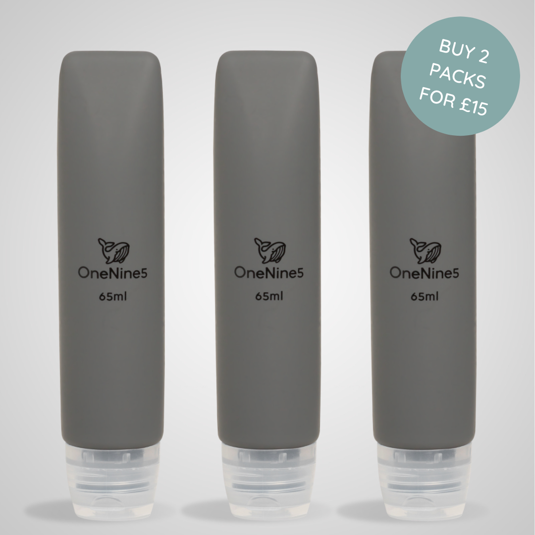 Three grey OneNine5 silicone travel bottles on a matching grey background. A black OneNine5 logo is visible on the front of the bottles that states a volume of 65ml.