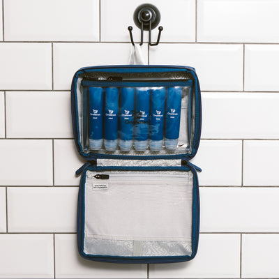 Six blue silicone travel bottles inside the clear toiletry pouch. The pouch is attached inside our OneNine5, Havelock Blue wash bag using the hanging hook in the bathroom